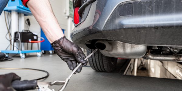 Woman looking under the hood of her blue car